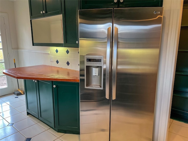 kitchen featuring decorative backsplash, light tile patterned flooring, stainless steel fridge with ice dispenser, and green cabinetry