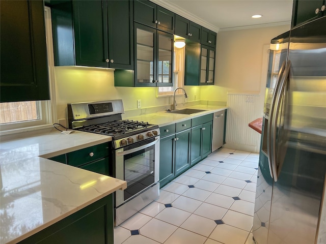 kitchen with light stone counters, ornamental molding, stainless steel appliances, sink, and green cabinetry