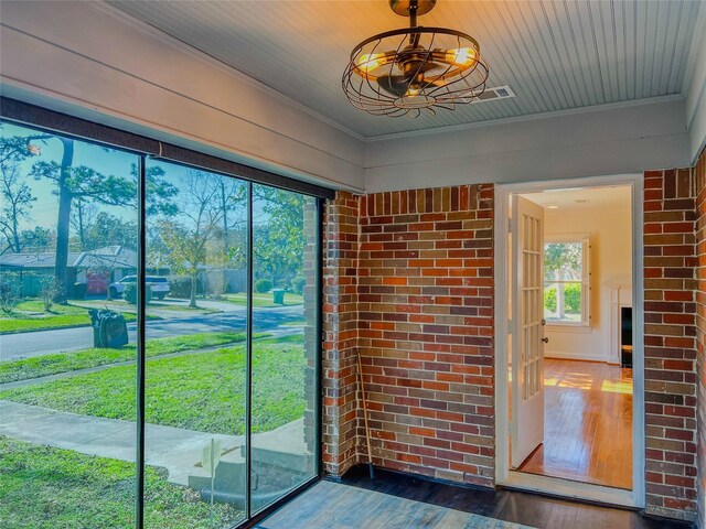 doorway with dark hardwood / wood-style floors and brick wall