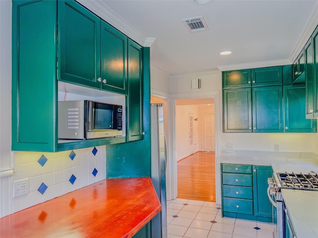 kitchen featuring light tile patterned flooring, ornamental molding, and appliances with stainless steel finishes