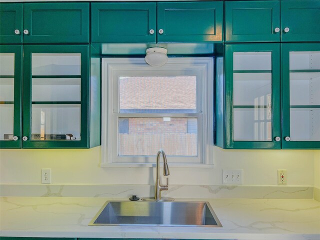 kitchen featuring light stone counters, sink, a healthy amount of sunlight, and green cabinetry