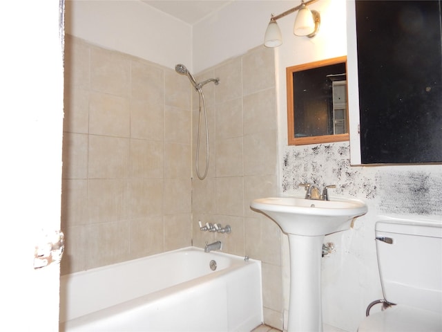 full bathroom featuring sink, tiled shower / bath, and toilet