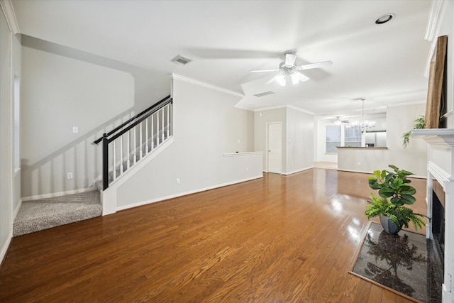 unfurnished living room featuring hardwood / wood-style floors, ceiling fan with notable chandelier, and crown molding