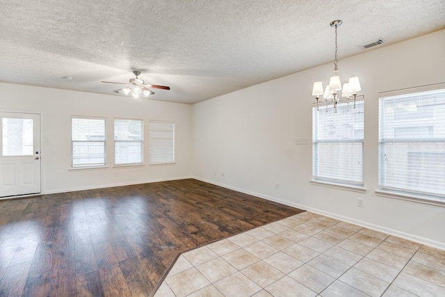 unfurnished room with a textured ceiling, plenty of natural light, ceiling fan with notable chandelier, and light hardwood / wood-style flooring