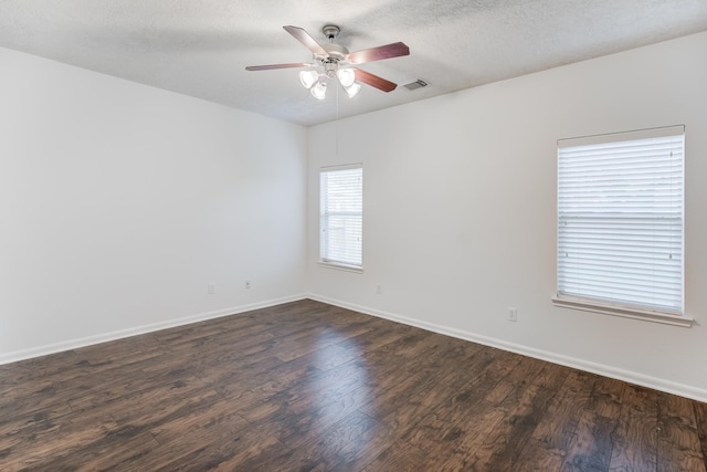 empty room featuring dark hardwood / wood-style floors, ceiling fan, and a textured ceiling