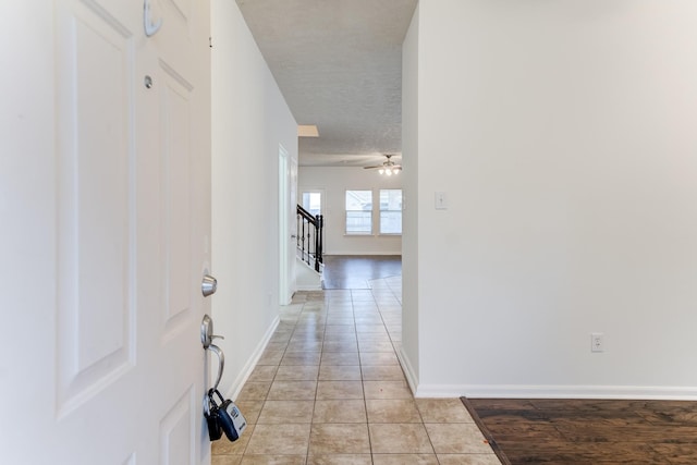 hall featuring light tile patterned floors and a textured ceiling