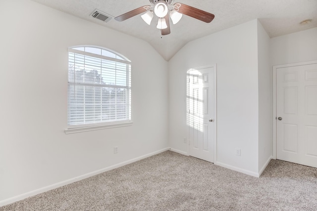 carpeted empty room featuring a textured ceiling, ceiling fan, and lofted ceiling