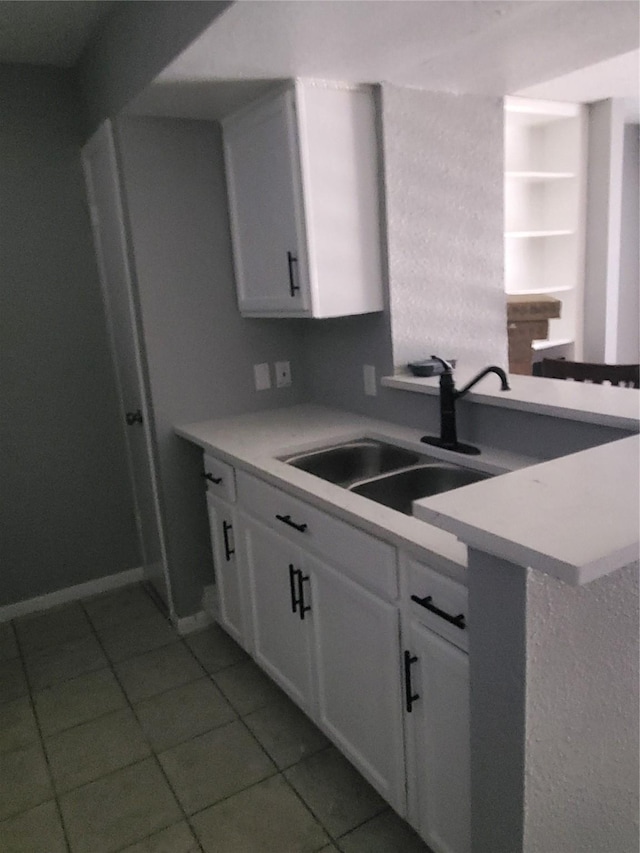 kitchen with kitchen peninsula, tile patterned floors, white cabinetry, and sink