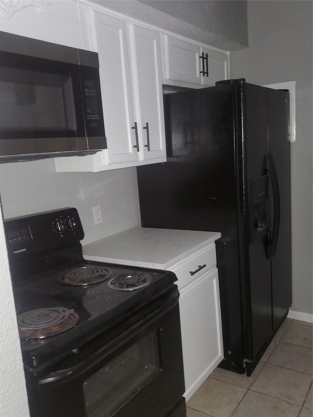 kitchen featuring white cabinets, light tile patterned flooring, and black appliances