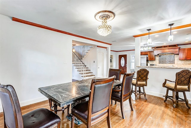 dining area featuring light hardwood / wood-style flooring, an inviting chandelier, and ornamental molding