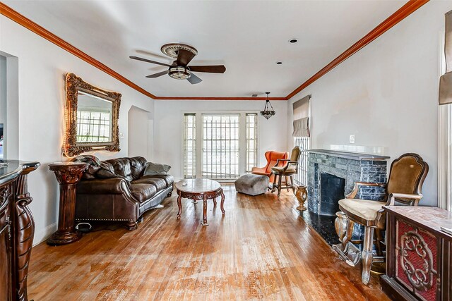 living room with a fireplace, light wood-type flooring, and ornamental molding