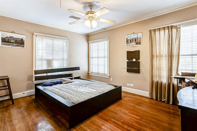 bedroom with multiple windows, ornamental molding, ceiling fan, and dark wood-type flooring