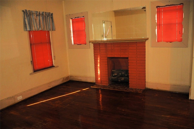 unfurnished living room with dark hardwood / wood-style floors and a brick fireplace