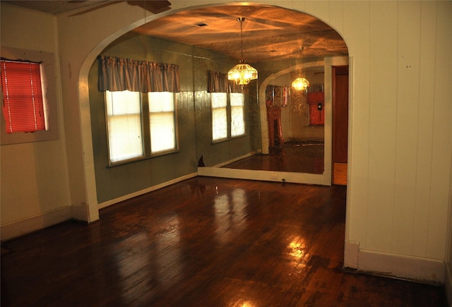 interior space featuring a notable chandelier, dark hardwood / wood-style floors, and wooden walls