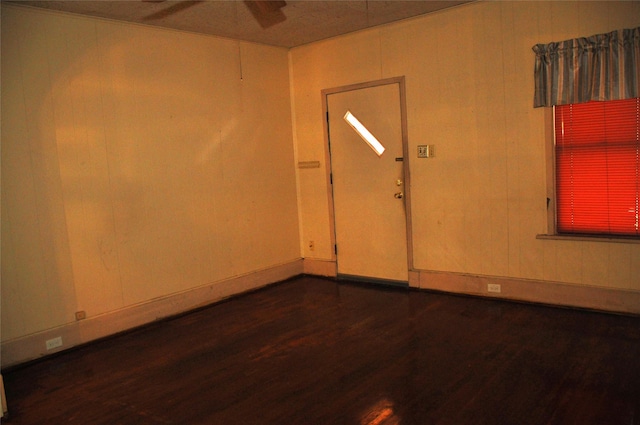 spare room featuring dark hardwood / wood-style flooring and wooden walls