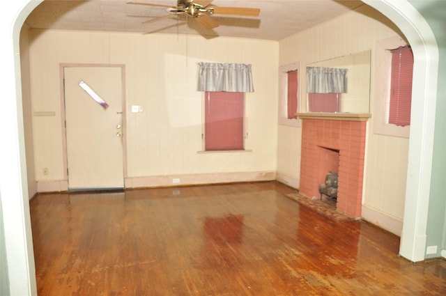 unfurnished living room with hardwood / wood-style floors, a brick fireplace, and ceiling fan