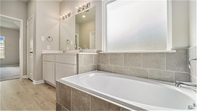 bathroom featuring vanity, wood-type flooring, and tiled bath