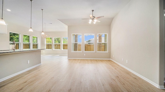 unfurnished living room featuring lofted ceiling, ceiling fan with notable chandelier, and light wood-type flooring