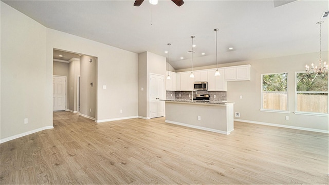 kitchen featuring white cabinets, a center island with sink, stainless steel appliances, and hanging light fixtures