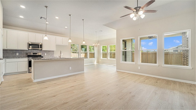 kitchen with white cabinets, light wood-type flooring, stainless steel appliances, and an island with sink