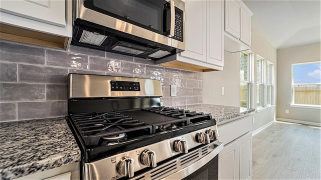 kitchen featuring white cabinetry, stainless steel appliances, light stone counters, and light wood-type flooring