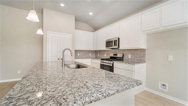 kitchen featuring sink, vaulted ceiling, decorative light fixtures, white cabinetry, and stainless steel appliances