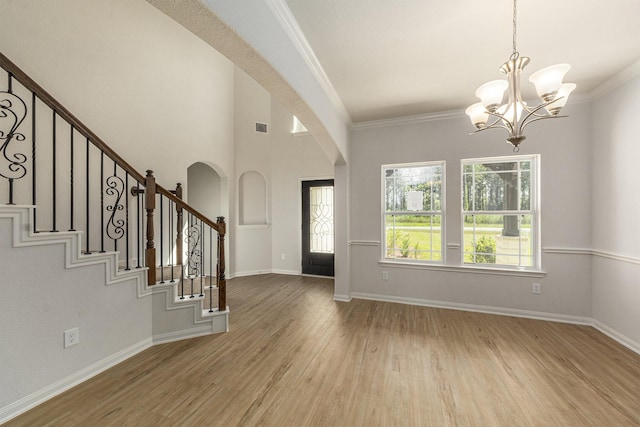 foyer entrance with an inviting chandelier, ornamental molding, and light wood-type flooring