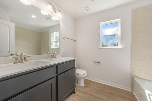 bathroom with a bathing tub, vanity, toilet, and wood-type flooring