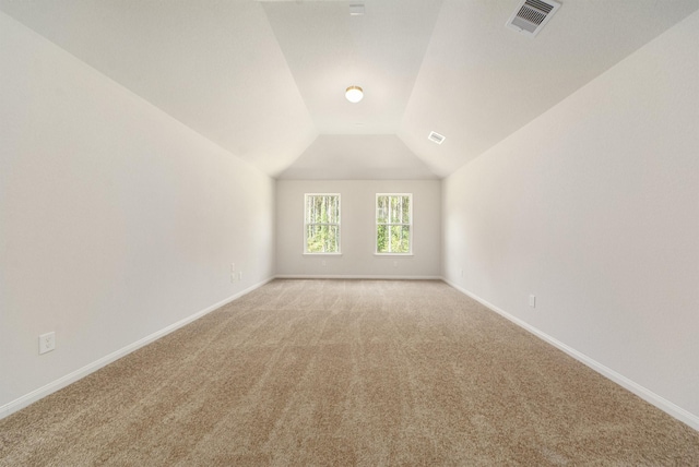 bonus room with light colored carpet and vaulted ceiling