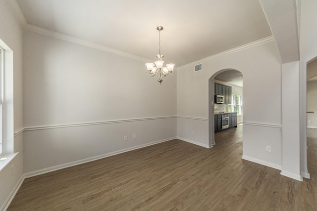 unfurnished room with dark hardwood / wood-style floors, crown molding, and an inviting chandelier