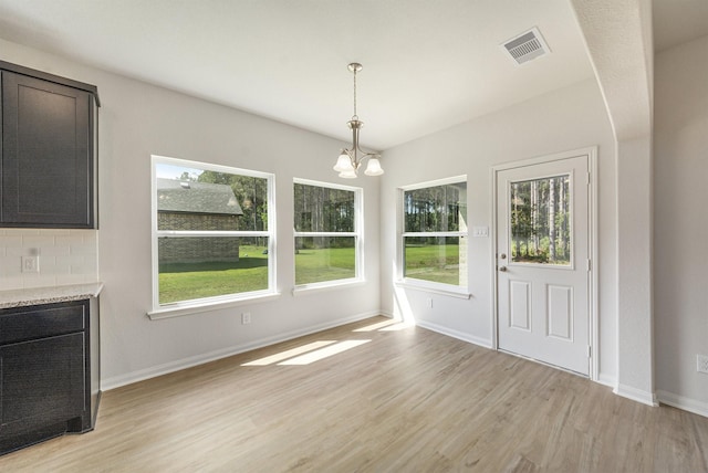 unfurnished dining area with a chandelier and light hardwood / wood-style floors