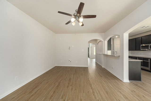 unfurnished living room featuring ceiling fan, light wood-type flooring, and sink