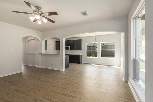 unfurnished living room featuring dark wood-type flooring and ceiling fan with notable chandelier