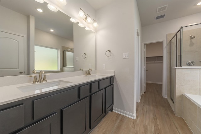 bathroom with hardwood / wood-style flooring, vanity, and plus walk in shower