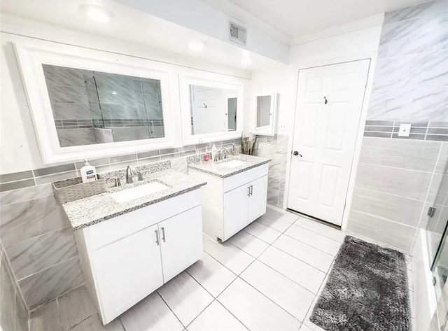 bathroom with tile patterned flooring, vanity, tile walls, and walk in shower