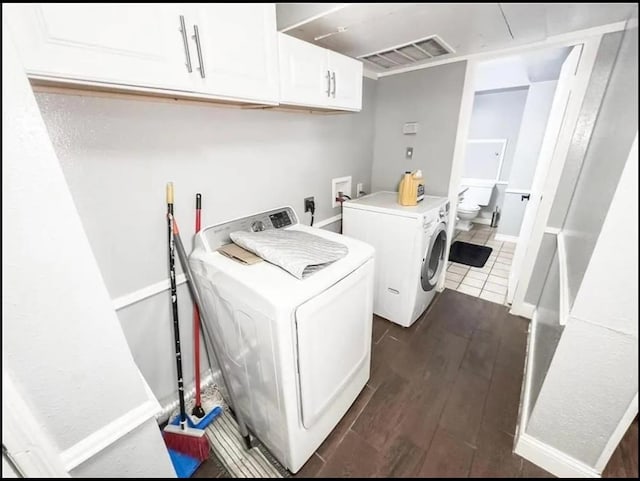 clothes washing area featuring cabinets, washer and clothes dryer, and dark wood-type flooring