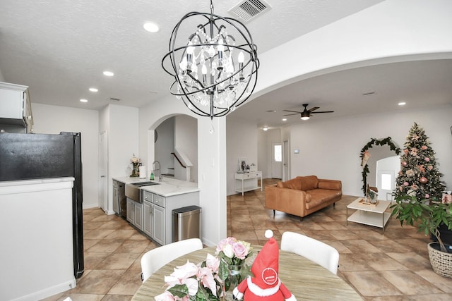 tiled dining area with a textured ceiling, ceiling fan with notable chandelier, and sink