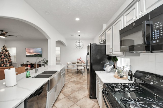 kitchen with light stone countertops, a healthy amount of sunlight, sink, and black appliances