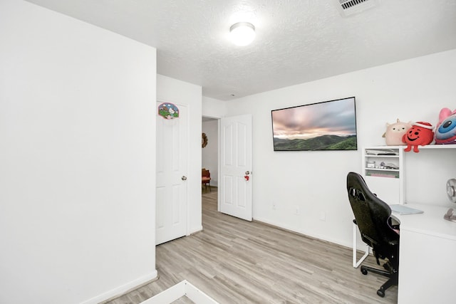 home office featuring light hardwood / wood-style floors and a textured ceiling