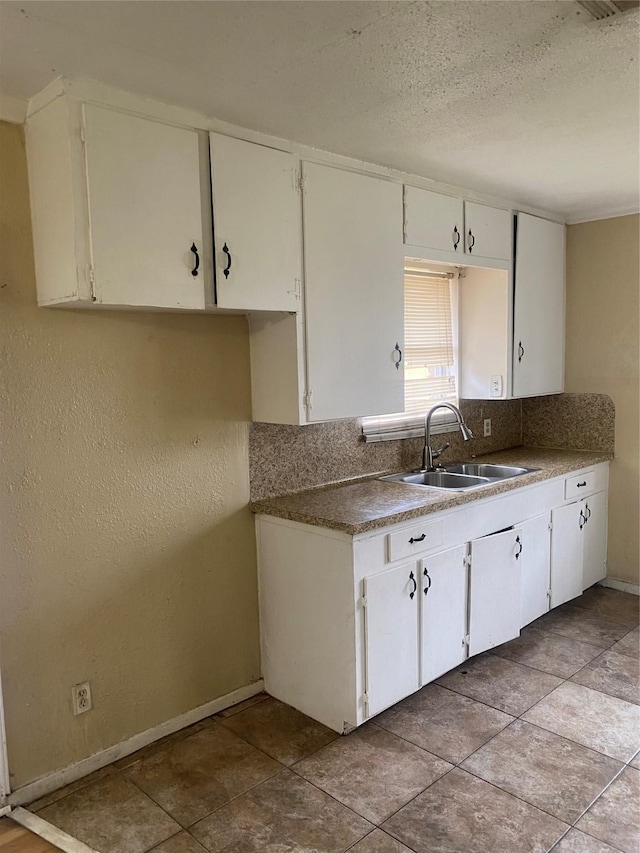 kitchen with decorative backsplash, white cabinetry, and sink