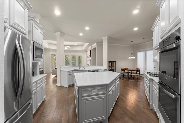 kitchen featuring dark wood-type flooring, ceiling fan with notable chandelier, sink, a kitchen island, and stainless steel appliances