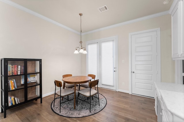 dining space with dark hardwood / wood-style flooring, an inviting chandelier, and ornamental molding