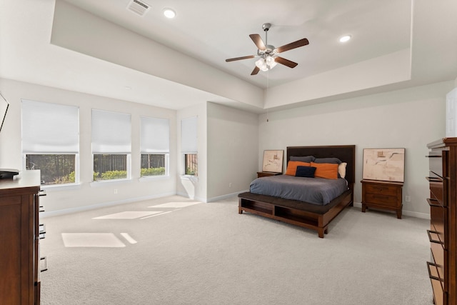 carpeted bedroom with a tray ceiling and ceiling fan