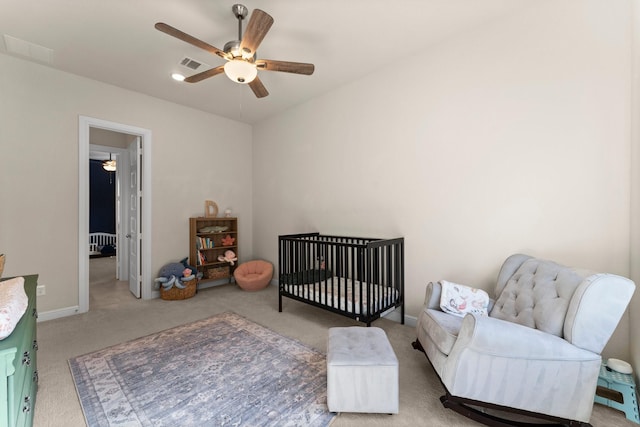 bedroom featuring carpet flooring, ceiling fan, and a nursery area