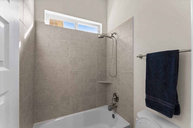 bathroom featuring tiled shower / bath combo and toilet