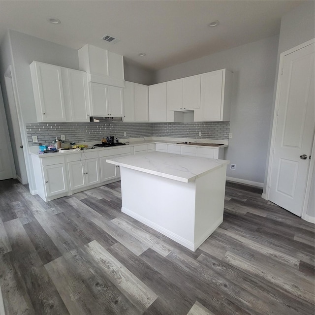 kitchen with white cabinets, wood-type flooring, tasteful backsplash, and a kitchen island