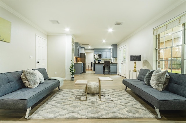 living room with crown molding and light hardwood / wood-style flooring