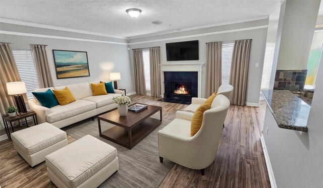 living room with hardwood / wood-style flooring, ornamental molding, a fireplace, and a textured ceiling