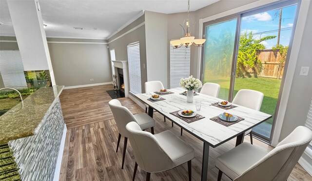 dining area featuring sink, hardwood / wood-style floors, ornamental molding, and an inviting chandelier