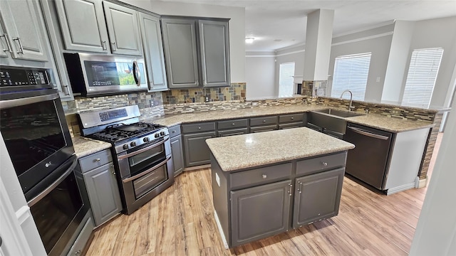 kitchen featuring kitchen peninsula, light wood-type flooring, stainless steel appliances, and gray cabinets